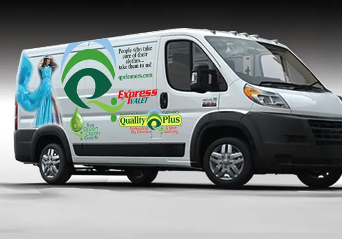 A white delivery van with colorful business graphics advertising dry cleaning and laundry services, including company logos, a website, and a woman in a blue dress.
